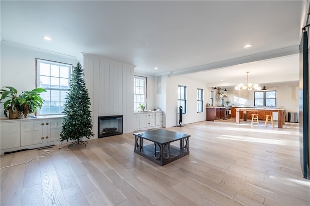 living room with a large fireplace, an inviting chandelier, a healthy amount of sunlight, and light wood-type flooring