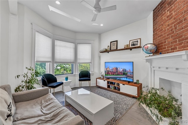 living room with ceiling fan, light hardwood / wood-style floors, and a brick fireplace