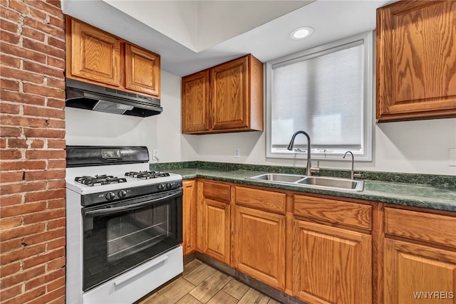 kitchen with sink, light hardwood / wood-style floors, brick wall, and white gas range oven