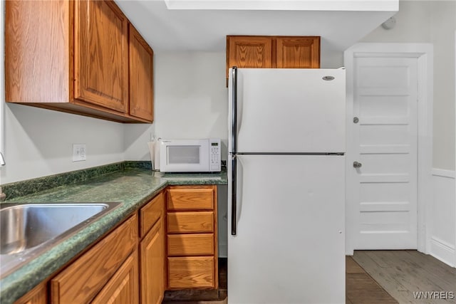 kitchen featuring wood-type flooring, white appliances, and sink