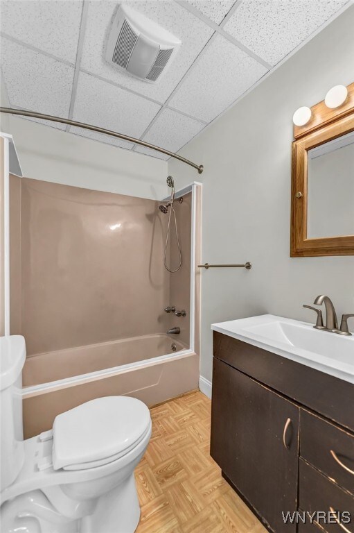 full bathroom with shower / tub combination, a paneled ceiling, parquet floors, and toilet