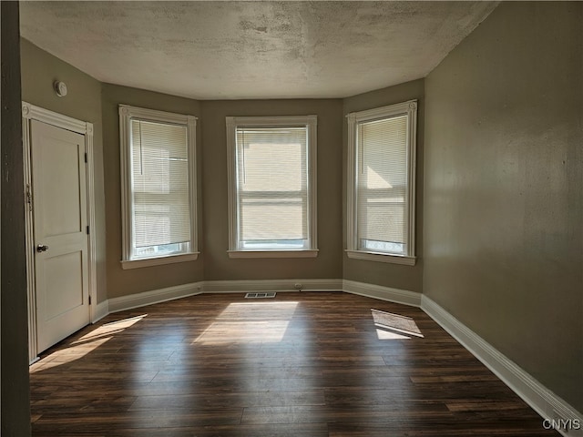 unfurnished room featuring dark hardwood / wood-style flooring and a textured ceiling