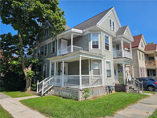 view of front facade with a porch, a balcony, and a front yard