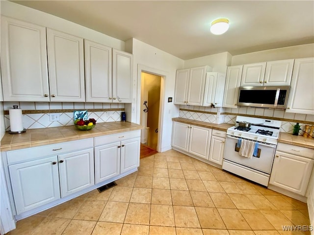 9 Mayfair Ln, Buffalo, NY 14201 - kitchen with stainless steel microwave, white gas range, tile counters, and white cabinetry