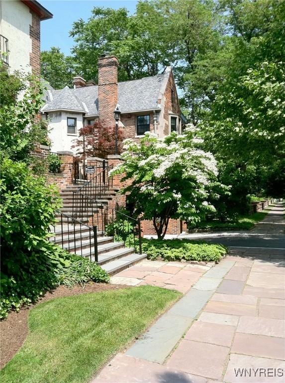 9 Mayfair Ln, Buffalo, NY 14201 - view of front of property with a chimney, stairs, brick siding, and stucco siding