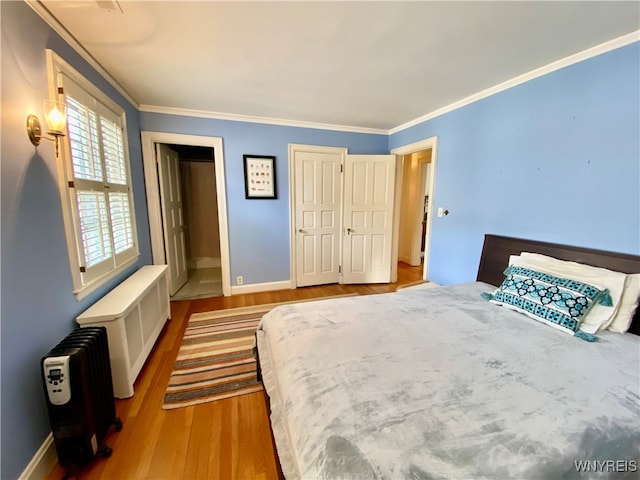 bedroom with light wood-type flooring, radiator, and ornamental molding