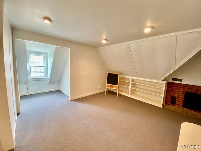 bonus room with carpet flooring, a fireplace, and vaulted ceiling