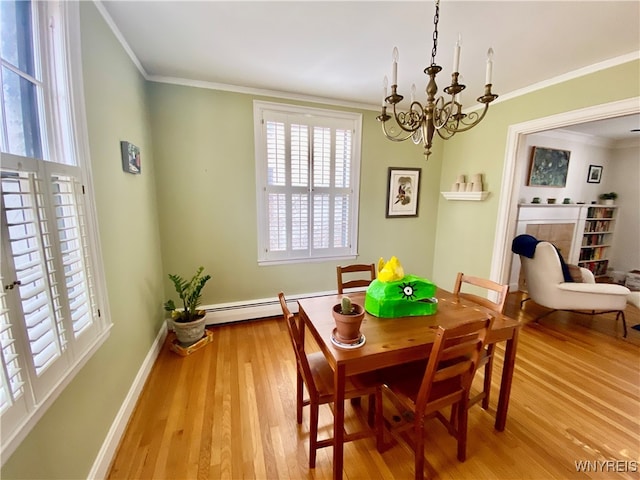 dining area with light hardwood / wood-style floors, crown molding, a tile fireplace, and a baseboard radiator