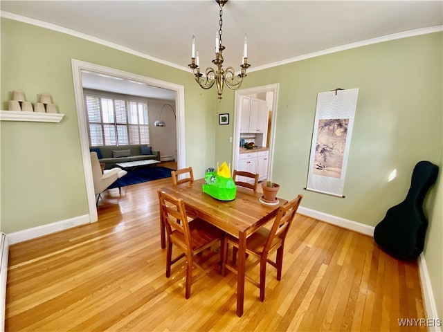 dining space featuring crown molding, light hardwood / wood-style flooring, and a notable chandelier