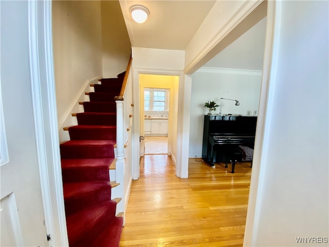 stairs featuring hardwood / wood-style flooring and ornamental molding