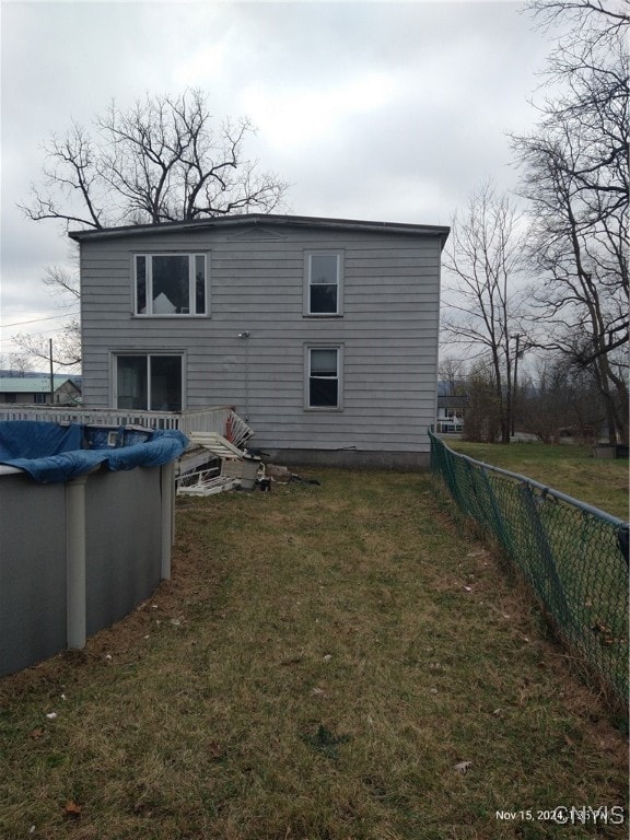 back of house featuring a lawn and a covered pool