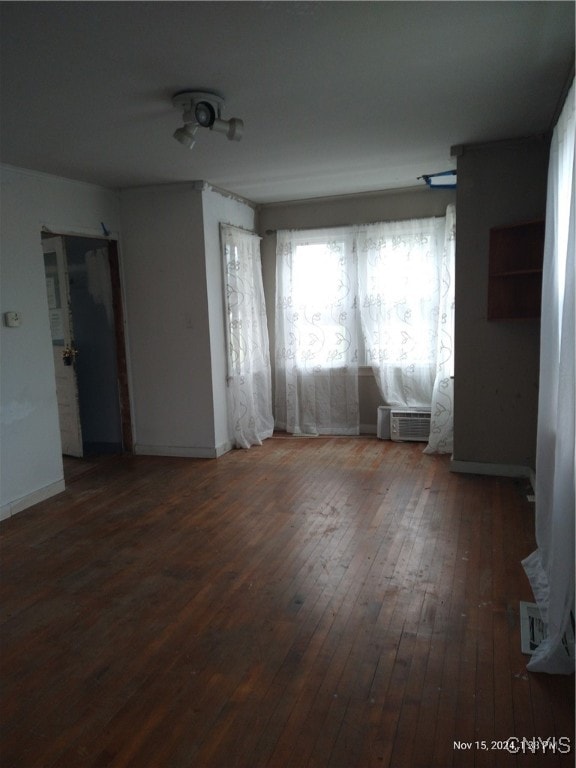 spare room featuring a wall mounted air conditioner and dark hardwood / wood-style floors