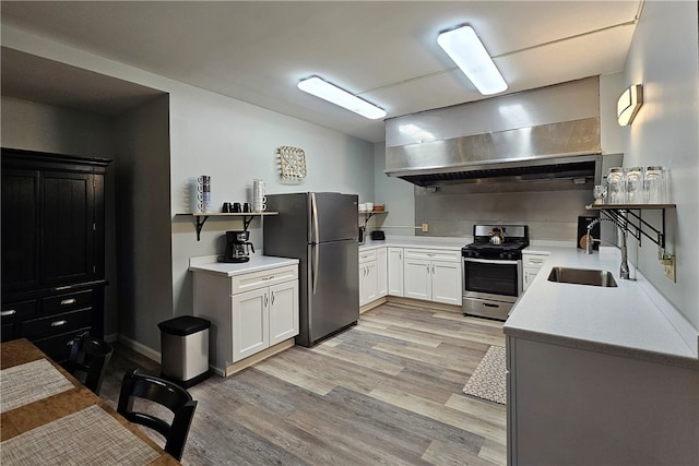 kitchen with stainless steel appliances, extractor fan, sink, white cabinets, and light hardwood / wood-style floors