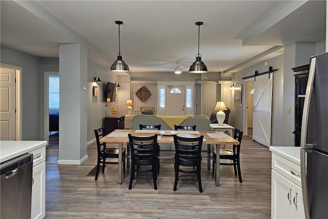 dining space featuring a barn door, ceiling fan, and hardwood / wood-style floors