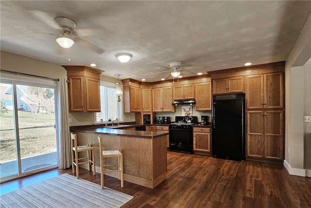 kitchen with sink, dark hardwood / wood-style floors, kitchen peninsula, decorative light fixtures, and black appliances