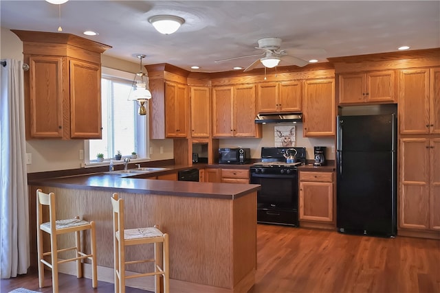 kitchen with black appliances, sink, kitchen peninsula, decorative light fixtures, and wood-type flooring