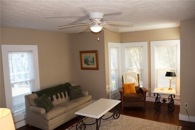 living room featuring a wealth of natural light, ceiling fan, dark wood-type flooring, and a textured ceiling