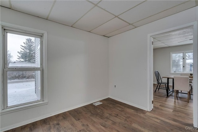 unfurnished room with dark hardwood / wood-style flooring and a drop ceiling