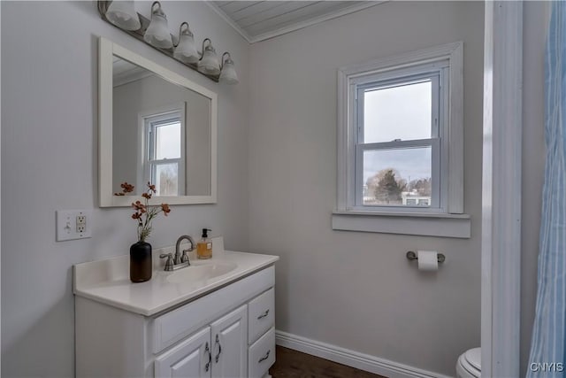 bathroom featuring a wealth of natural light, crown molding, vanity, and toilet