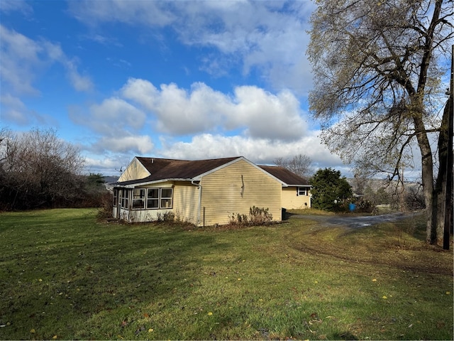 view of side of property featuring a sunroom and a yard