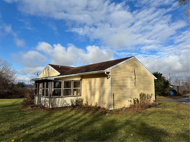 view of side of property with a sunroom and a lawn