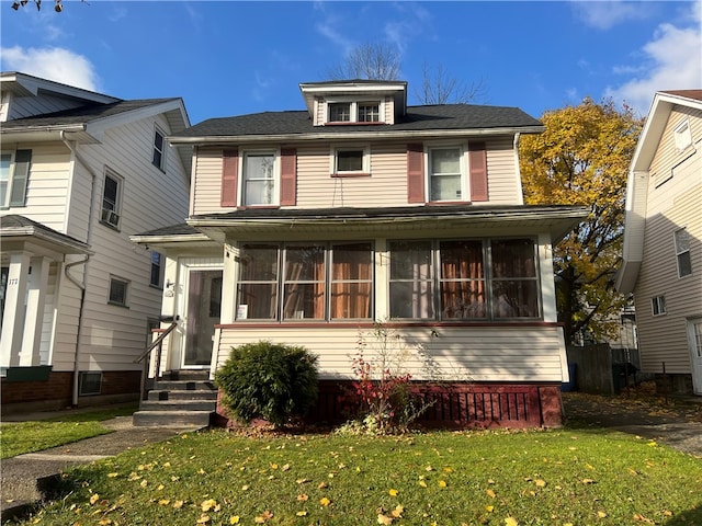 view of front of home with a sunroom and a front yard