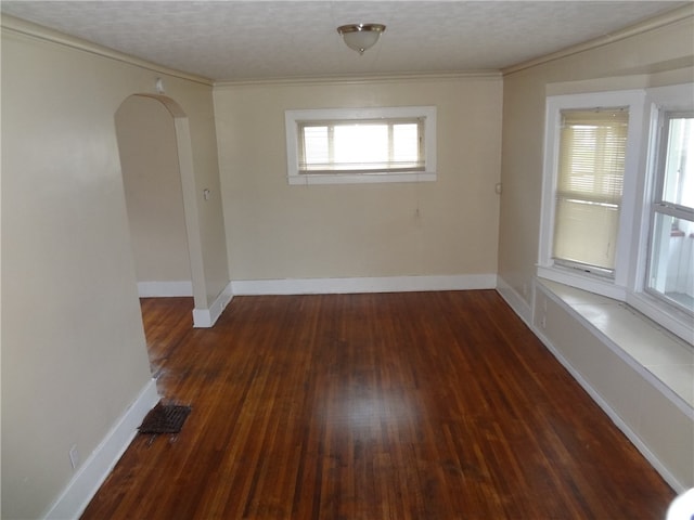 unfurnished room with a textured ceiling, dark hardwood / wood-style floors, and ornamental molding