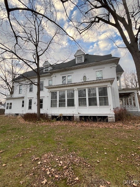 rear view of house featuring a lawn and a sunroom