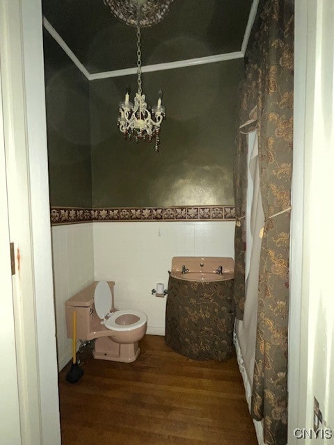 bathroom featuring toilet, wood-type flooring, sink, and an inviting chandelier