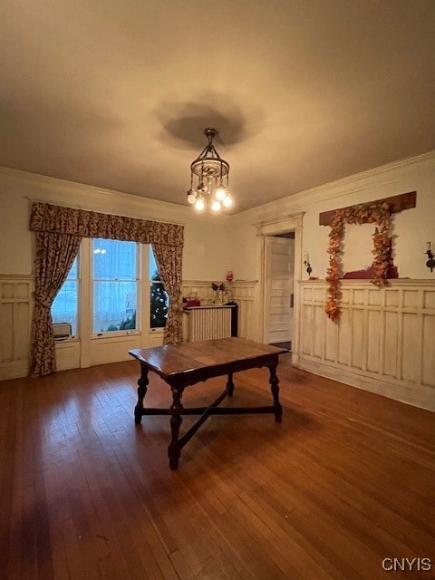 dining space with crown molding, dark hardwood / wood-style flooring, a notable chandelier, and radiator heating unit