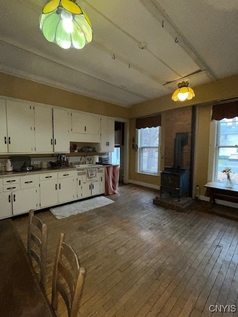 kitchen featuring white cabinets, plenty of natural light, dark hardwood / wood-style flooring, and a wood stove