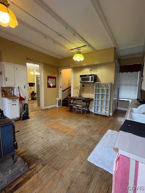 interior space with hardwood / wood-style flooring, a wall mounted air conditioner, white cabinetry, and a chandelier