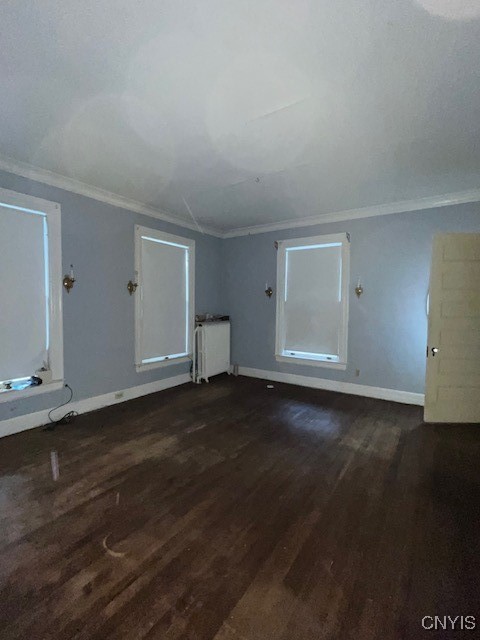 unfurnished room with crown molding, radiator, and dark wood-type flooring