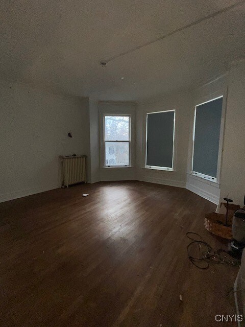 spare room featuring dark hardwood / wood-style floors, radiator heating unit, and a textured ceiling