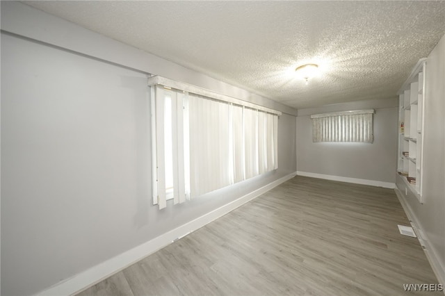 spare room with a textured ceiling, hardwood / wood-style flooring, and a healthy amount of sunlight