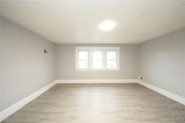 spare room featuring a textured ceiling and light wood-type flooring