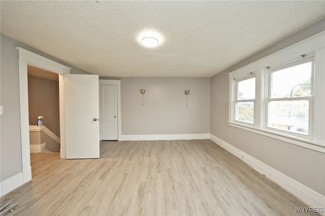 empty room with light hardwood / wood-style floors and a textured ceiling