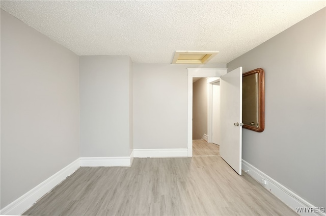 spare room with light hardwood / wood-style flooring and a textured ceiling