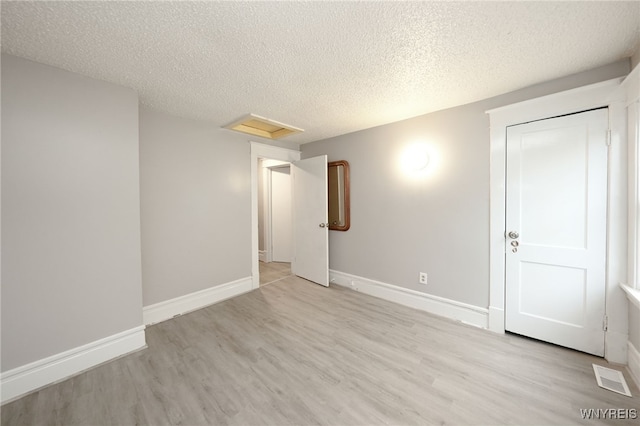 spare room featuring light hardwood / wood-style floors and a textured ceiling