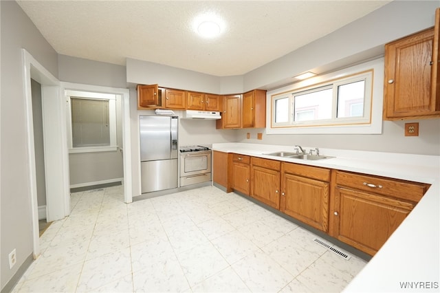 kitchen featuring a textured ceiling, stainless steel fridge, sink, and white electric stove