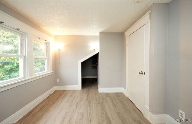 additional living space with a textured ceiling and light wood-type flooring