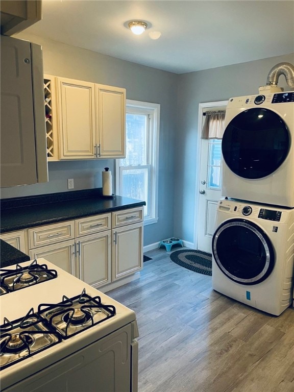 kitchen featuring stacked washer / dryer, light hardwood / wood-style flooring, and white gas range oven