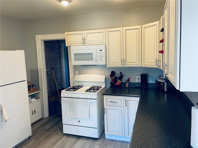 kitchen with white appliances, hardwood / wood-style flooring, and white cabinetry