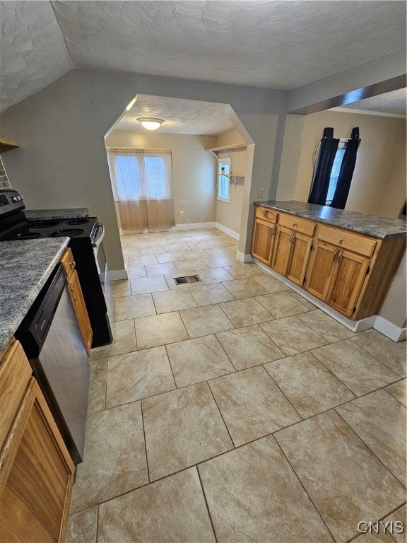 kitchen with light tile patterned floors, lofted ceiling, a textured ceiling, and appliances with stainless steel finishes