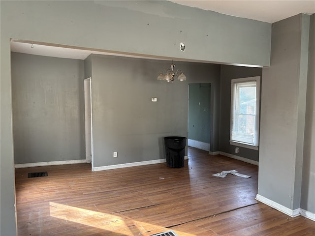 spare room featuring hardwood / wood-style floors and a chandelier