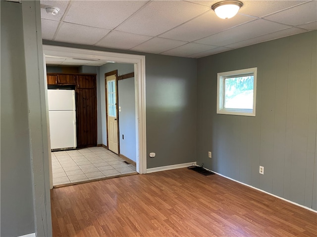 spare room featuring light hardwood / wood-style flooring and a drop ceiling