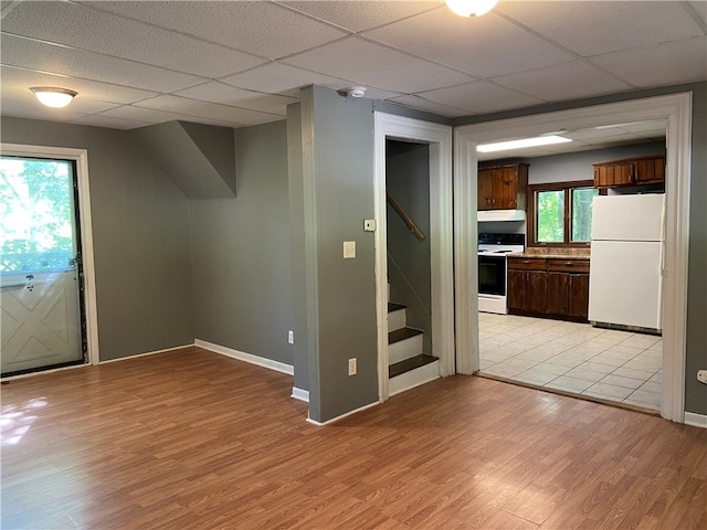 interior space with a drop ceiling, white fridge, and light hardwood / wood-style flooring