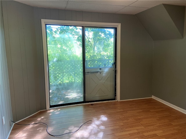 doorway to outside featuring a drop ceiling, a healthy amount of sunlight, lofted ceiling, and light hardwood / wood-style flooring