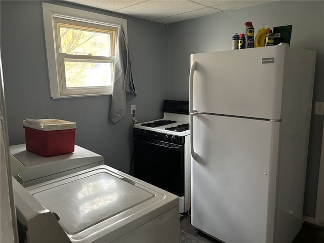 kitchen with a drop ceiling, white appliances, and washer / clothes dryer