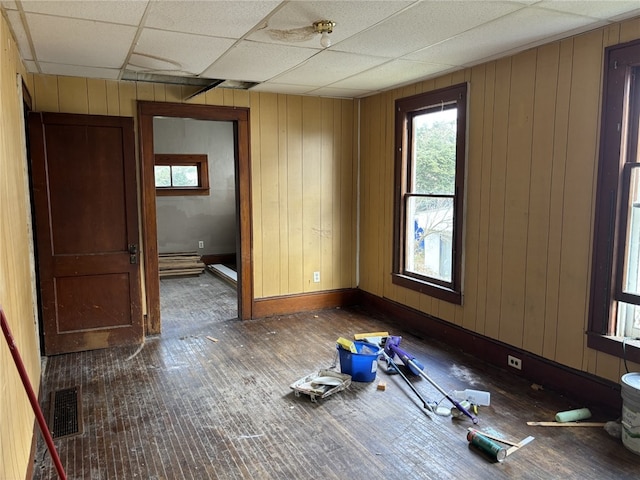 spare room featuring dark hardwood / wood-style flooring, a drop ceiling, and wood walls